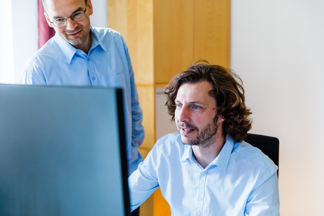 Zwei Personen schauen auf einen Monitor.