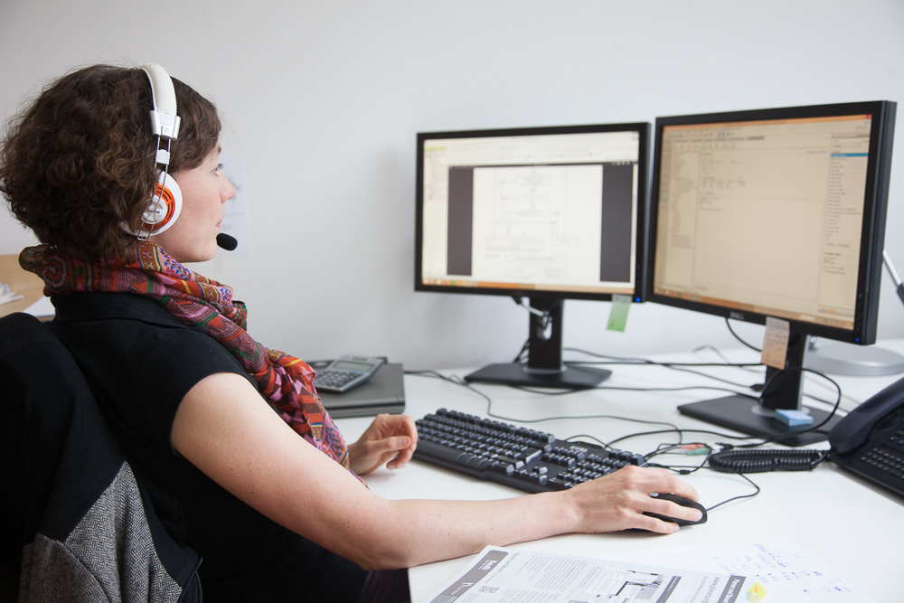 Eine Person sitzt vor zwei Monitoren mit einem headset auf