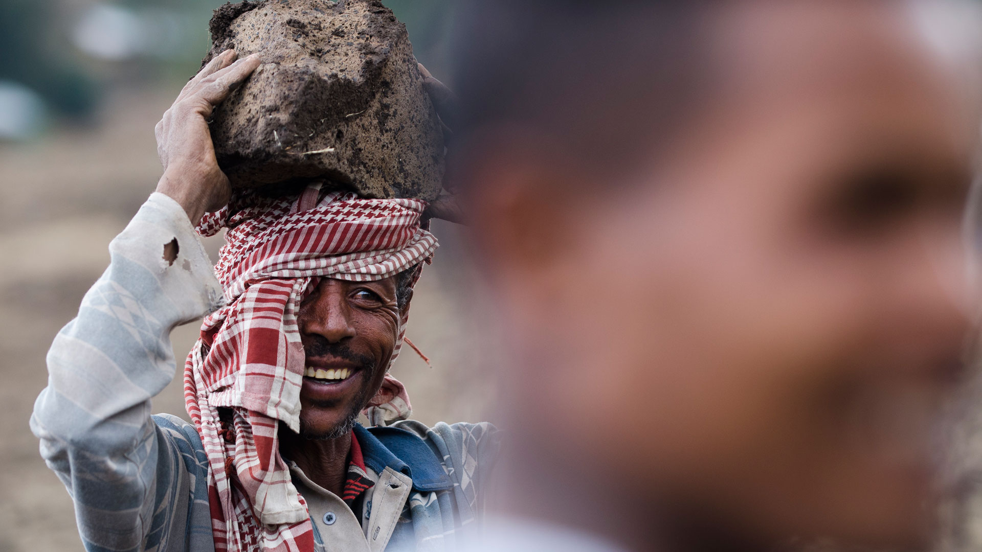 Mann trägt einen Stein für den Bau von Gabionen