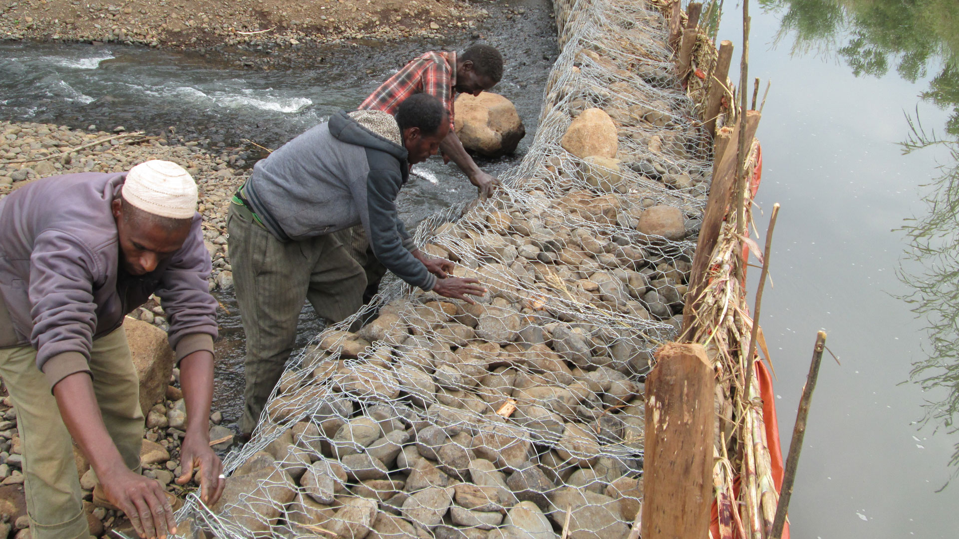 Bauern bauen aus Steinen und Drahtkörben Gabionen